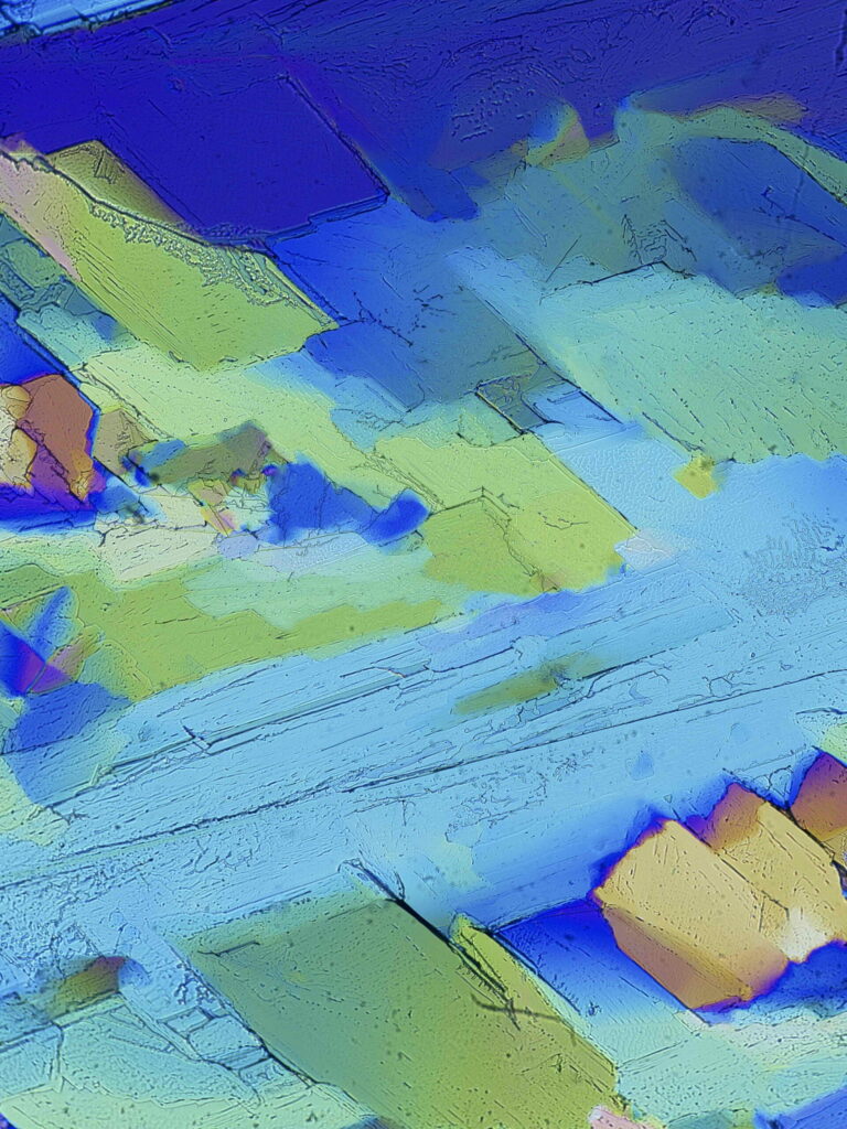 Alain Spriet_Aplats de couleur à dominante bleue ayant l’aspect d’une peinture au couteau, évoquant une rivière entre une colline verdoyante et des rochers. Cristallisation de thiocyanate de guanidinium, désinfectant actif contre les virus